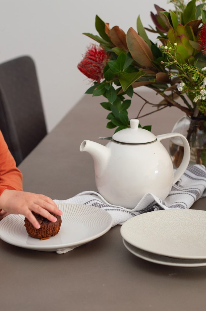 a little hand grabbing a carrot cake muffin