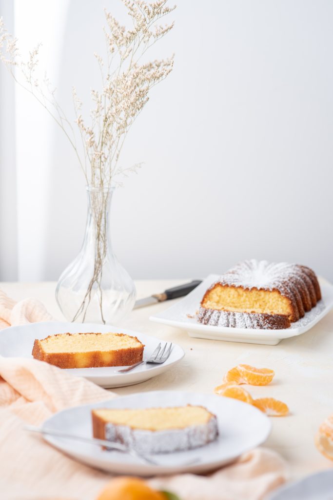 A scene with the pound cake with some slices in plates. 